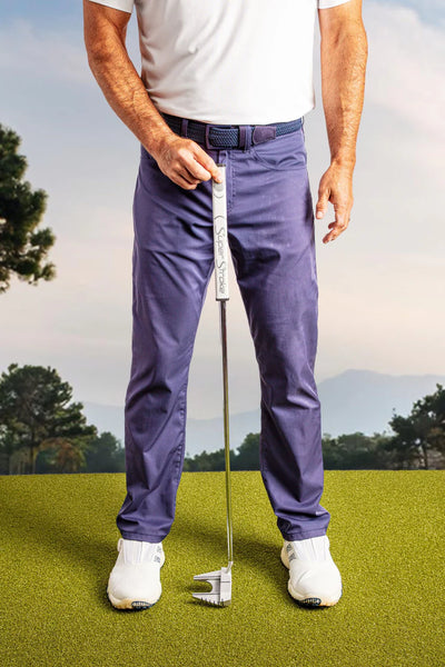 man holding a putter at hid midline to measure slope while on putting green